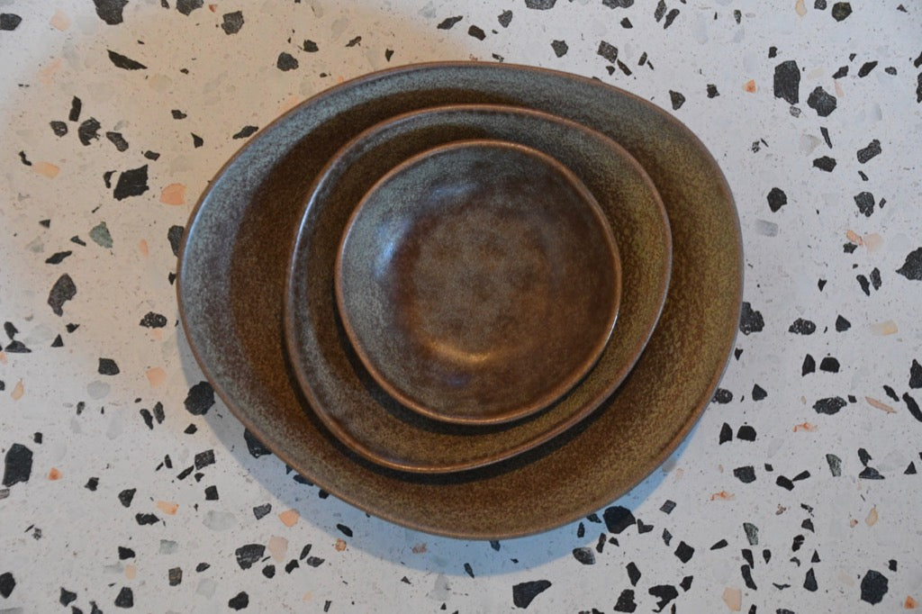 Stack of brown ceramic plates on a speckled surface
