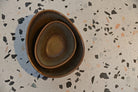 Three ceramic bowls stacked on a terrazzo countertop