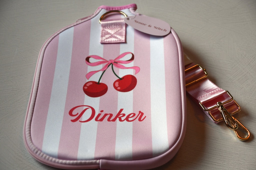 Pink and white striped pouch with cherry design and 'Dinker' branding on a light gray background