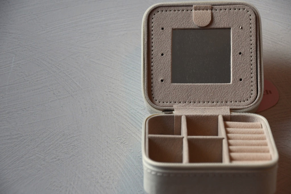 Beige jewelry box with compartments on a gray surface
