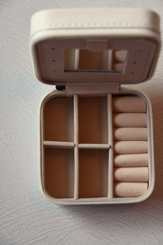 Beige jewelry box with compartments on a light gray surface