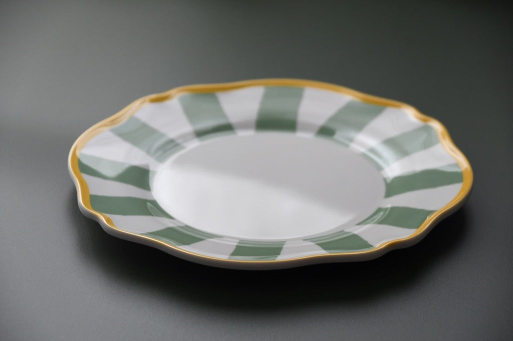 Ceramic plate with green and gold decorative rim on a gray background