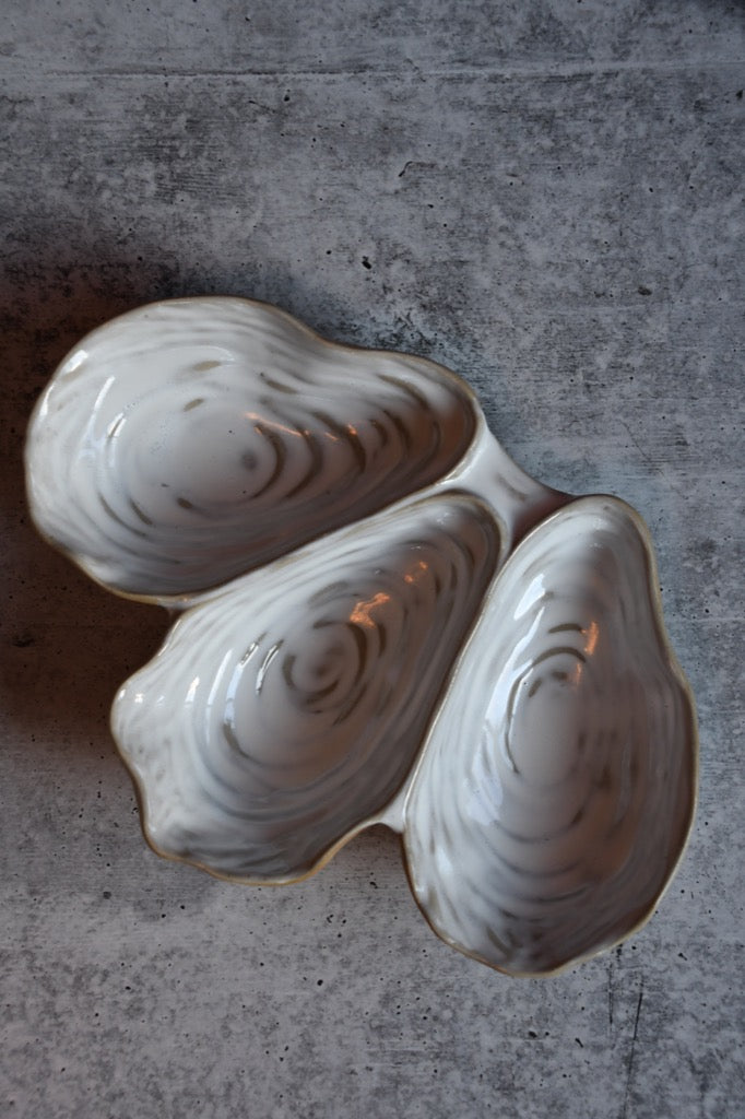 Two ceramic oyster shells on a textured surface