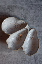 Two ceramic oyster shells on a textured surface