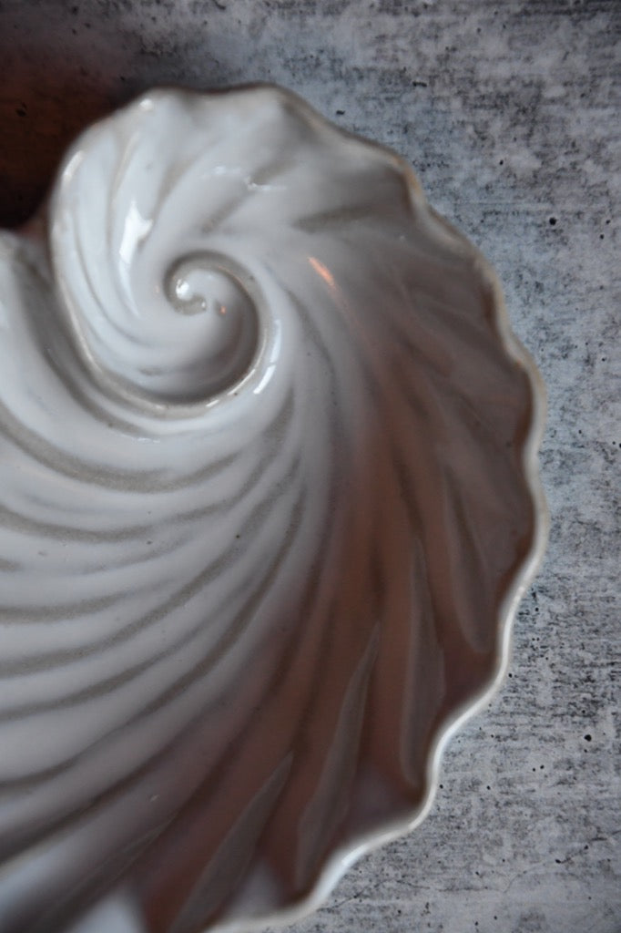 Ceramic shell-shaped dish on a textured surface