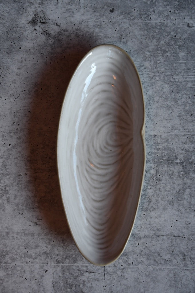 White ceramic dish with wavy pattern on a gray concrete surface