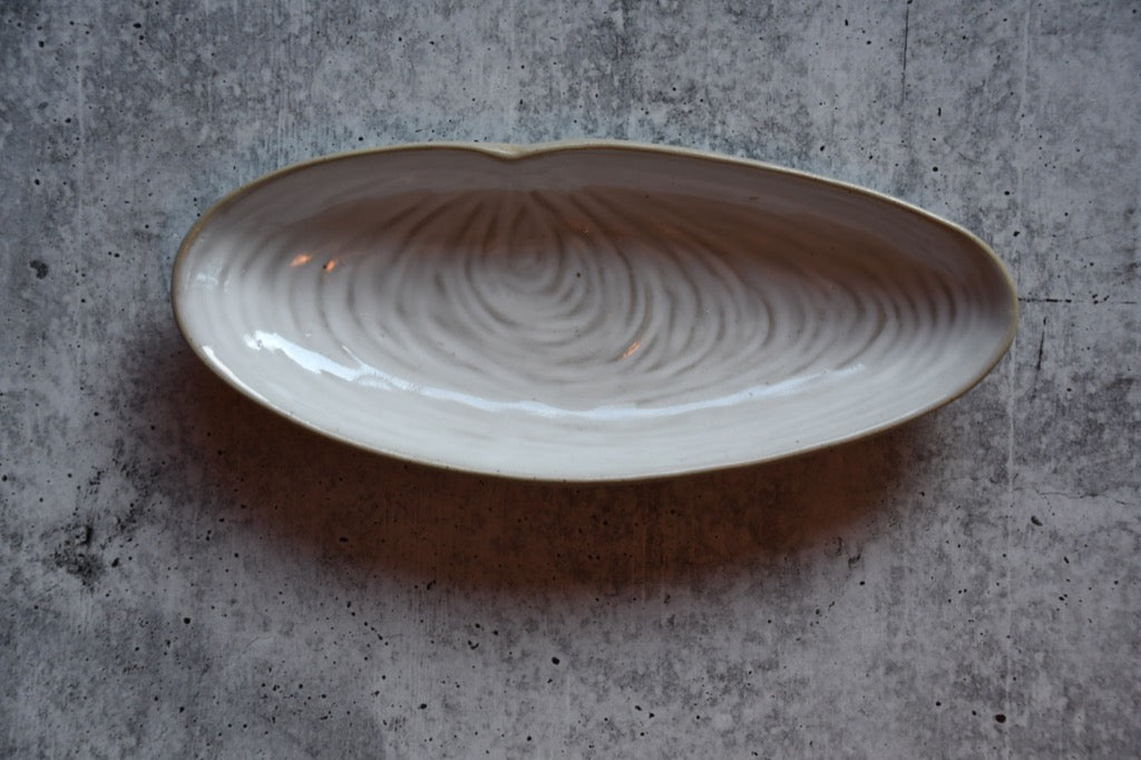 Ceramic dish with wavy pattern on a gray concrete surface