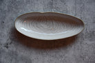 Ceramic dish with wavy pattern on a gray concrete surface