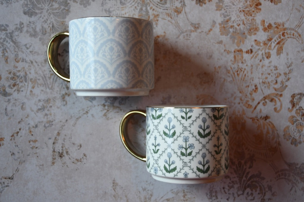Two patterned mugs on a textured surface