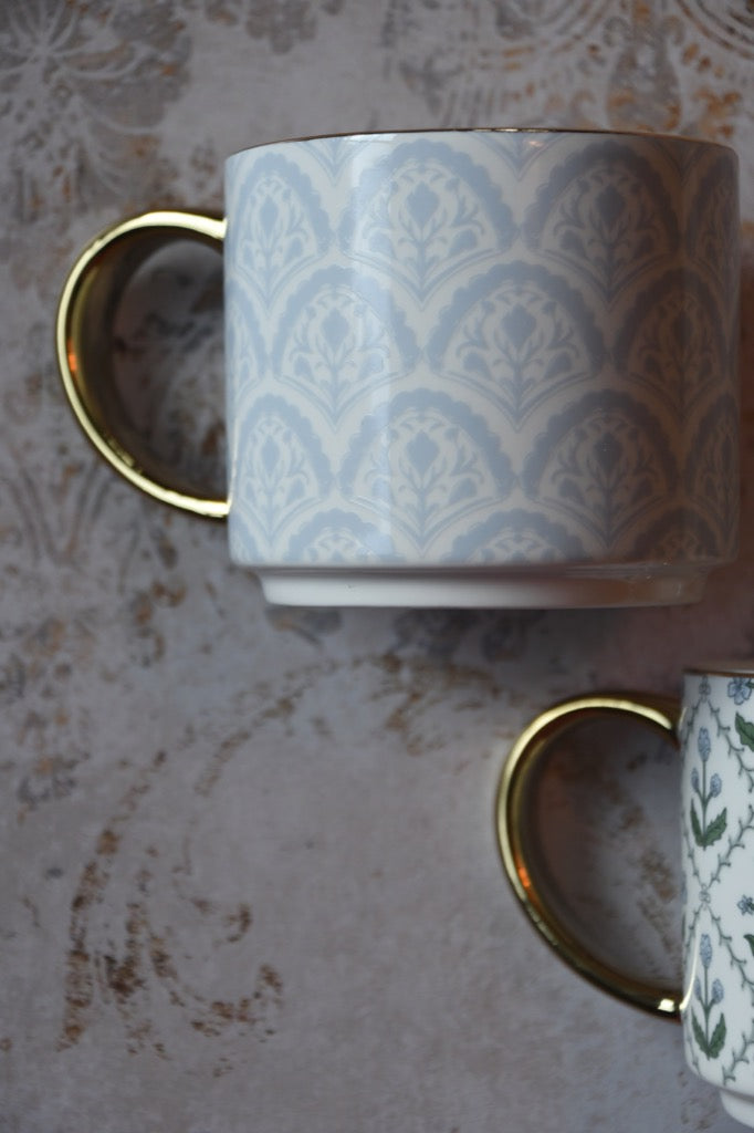 Patterned mug with gold handle on a textured surface