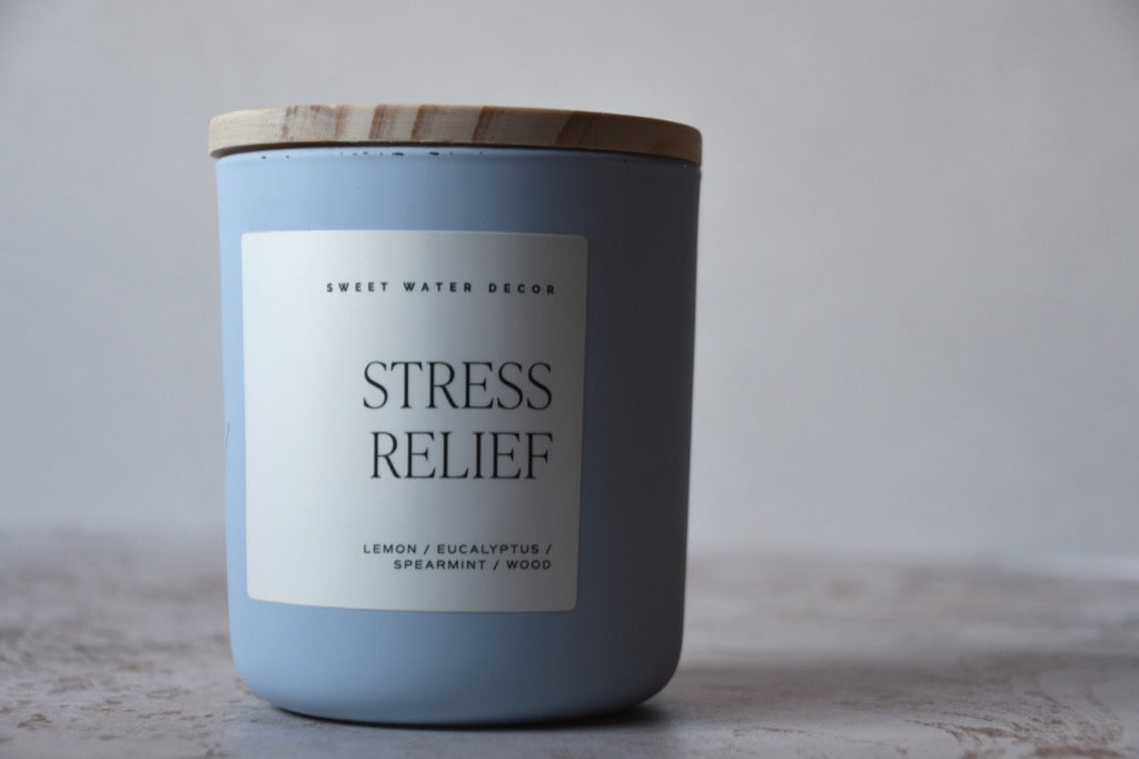 Candle labeled 'Stress Relief' with a wooden lid on a neutral background