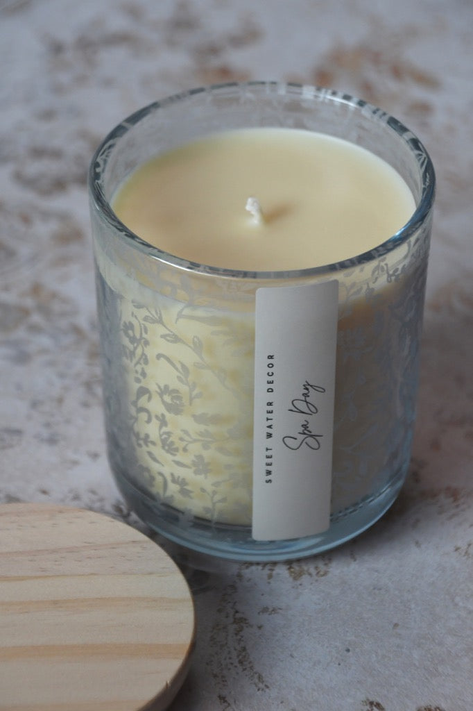 Candle in a glass jar with a decorative label on a textured surface