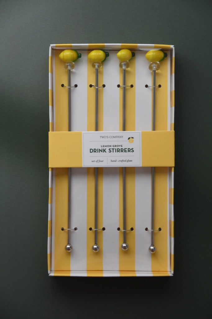 Set of drink stirrers in a yellow and white striped box on a dark background
