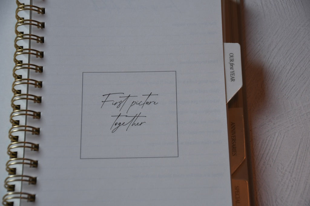 Notebook with 'First picture together' text on a plain background