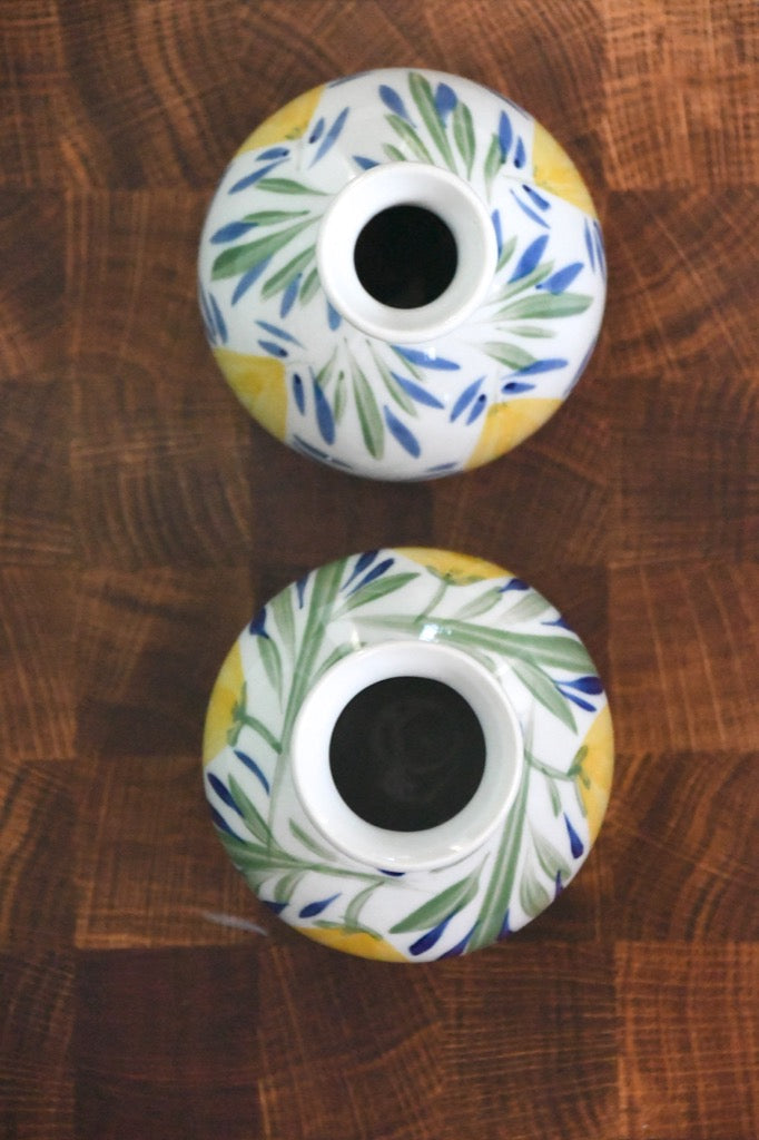 Two ceramic candle holders with floral patterns on a wooden surface