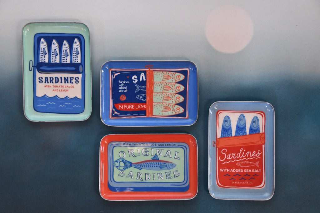 Four vintage-style sardine can labels on a textured surface