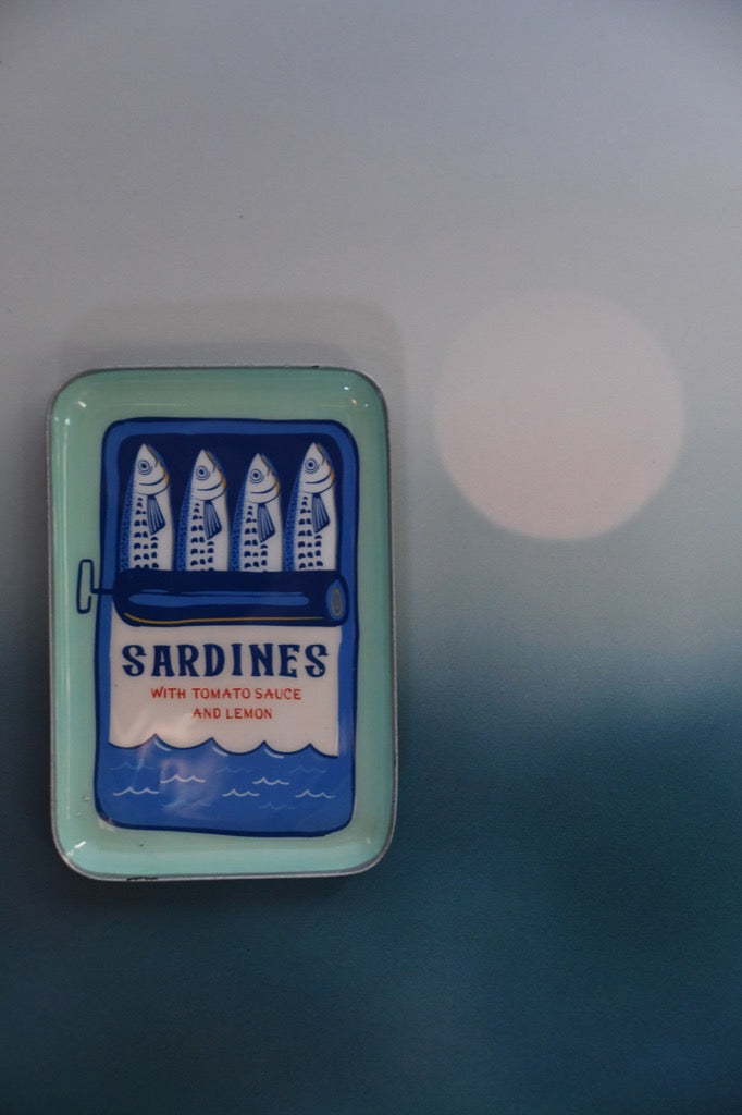 Sardine can-shaped container with sardine illustration on a blue background