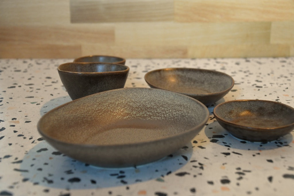 Set of four ceramic bowls on a speckled countertop with a wooden backsplash.