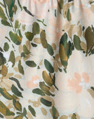 Floral patterned fabric with green leaves and pink flowers on a beige background