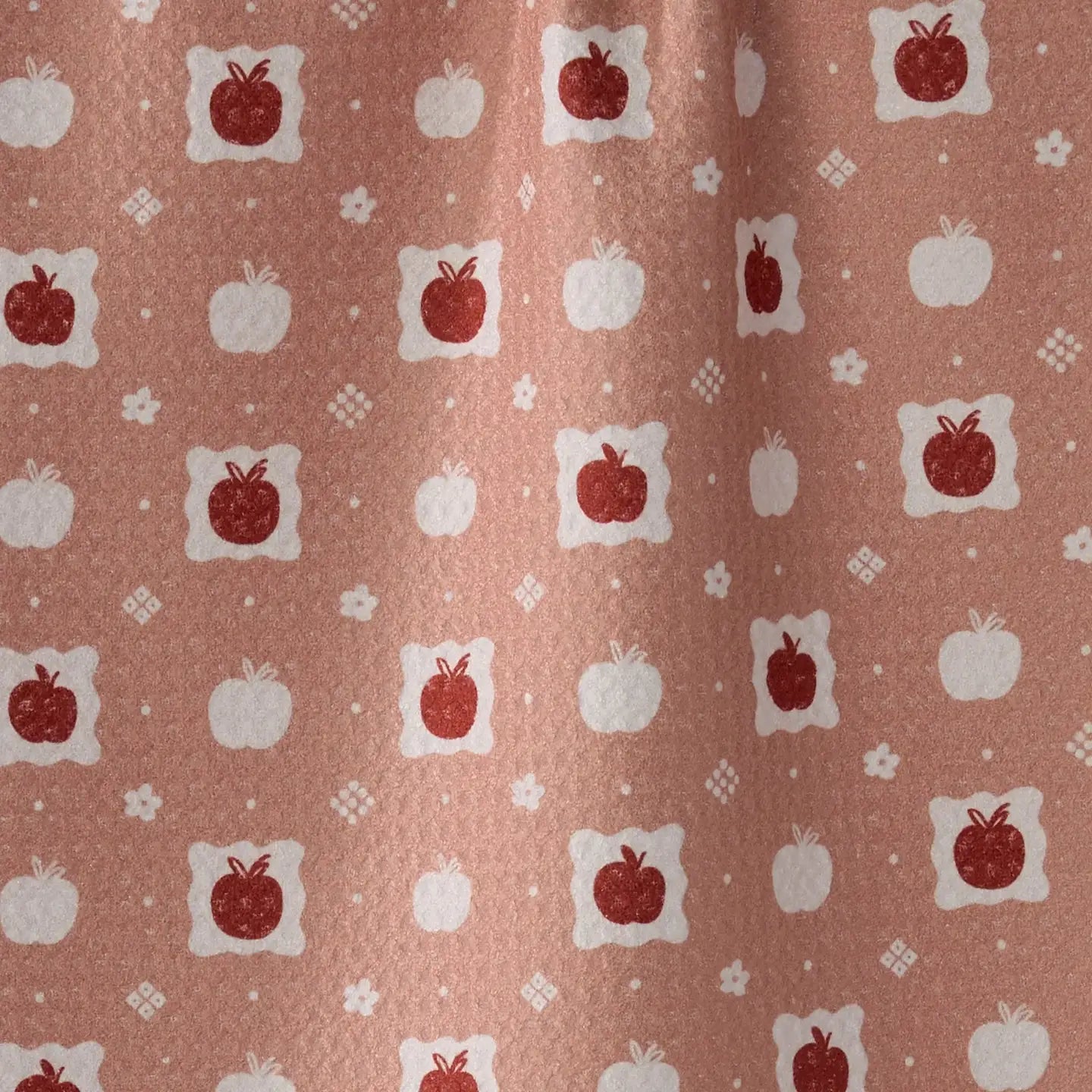 A close-up of a fabric or wallpaper pattern featuring red apples and white pumpkins on a dusty terracotta background.