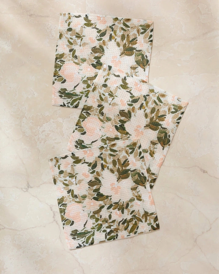 Two floral-patterned towels on a textured beige surface