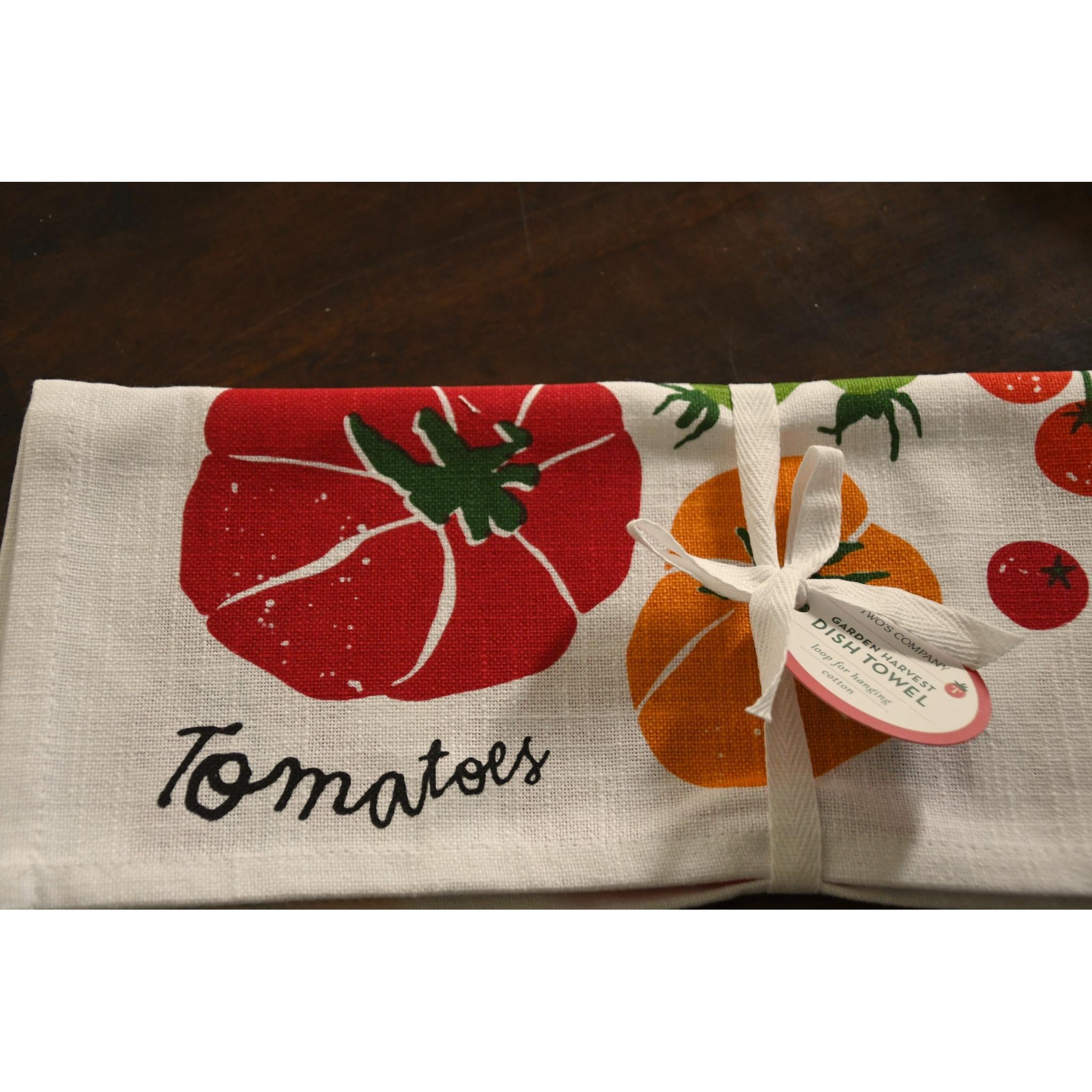 Folded towel with tomato design and text on a wooden surface