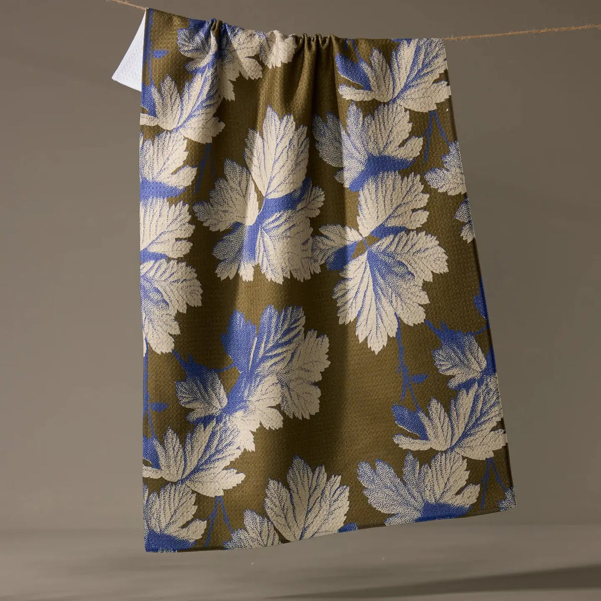 Floral patterned fabric hanging on a line against a plain background